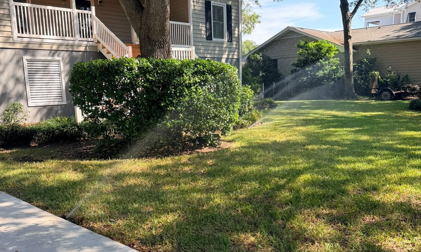 A Bess Irrigation sprinkler system actively watering a lush green lawn in morning light